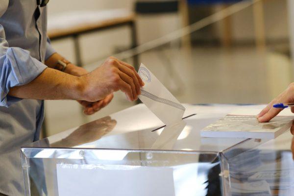 εικόνα που δείχνει άνδρα να ρίχνει τον φάκελο με το ψηφοδέλτιο στην κάλπη