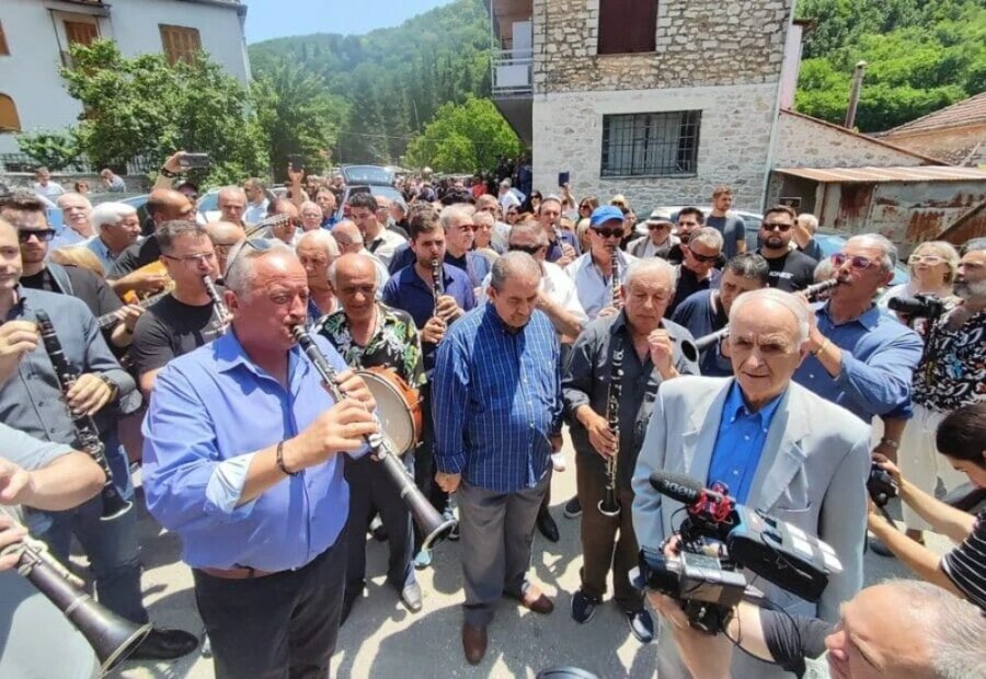 εικόνα που δείχνει μουσικούς να παίζουν το τελευταίο μοιρολόι για τον Πετρολούκα Χαλκιά ανάμεσα σε πλήθος κόσμου στο Πωγώνι