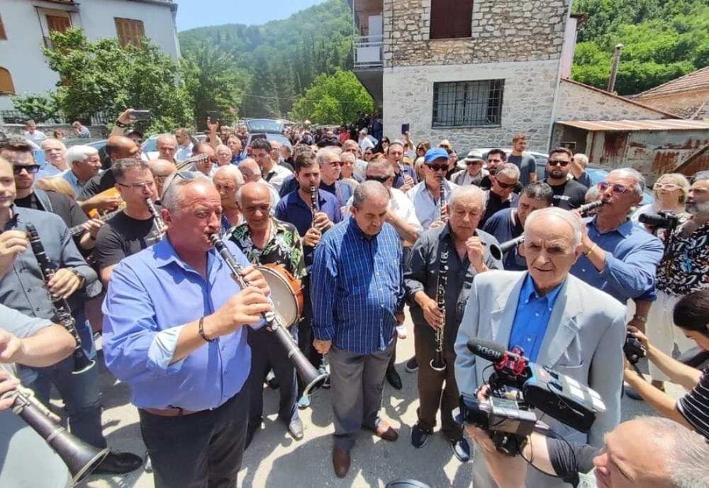 εικόνα που δείχνει μουσικούς να παίζουν το τελευταίο μοιρολόι για τον Πετρολούκα Χαλκιά ανάμεσα σε πλήθος κόσμου στο Πωγώνι