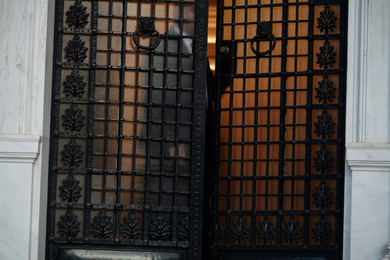 εικόνα που δείχνει την κεντρική είσοδο του Μεγάρου Μαξίμου, με μια σκιά να διακρίνεται πίσω από την κλειστή πόρτα