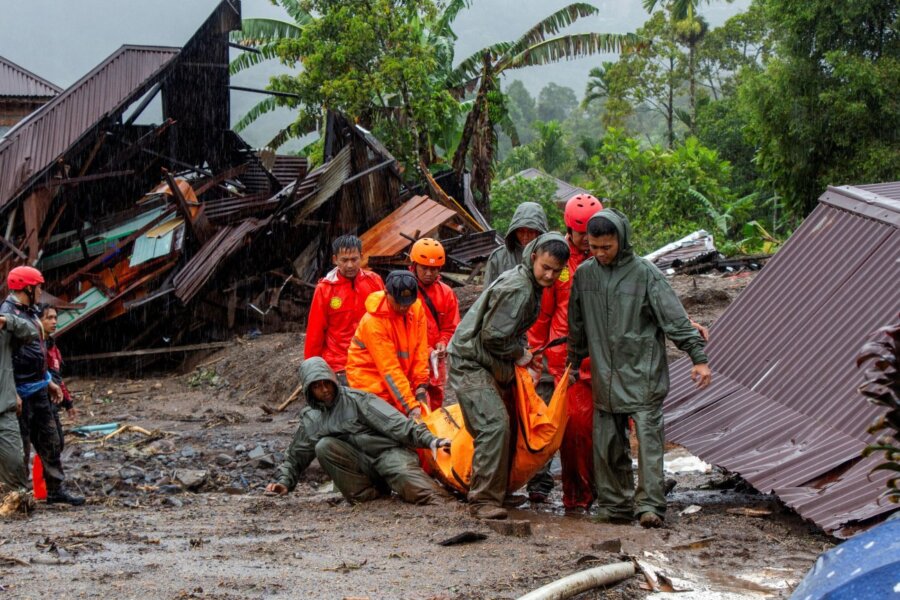 εικόνα που δείχνει διασώστες να μεταφέρουν ένα από τα θύματα που έχασαν τη ζωή τους στις πλημμύρες που έπληξαν περιοχή της Δυτικής Σουμάτρας στην Ινδονησία